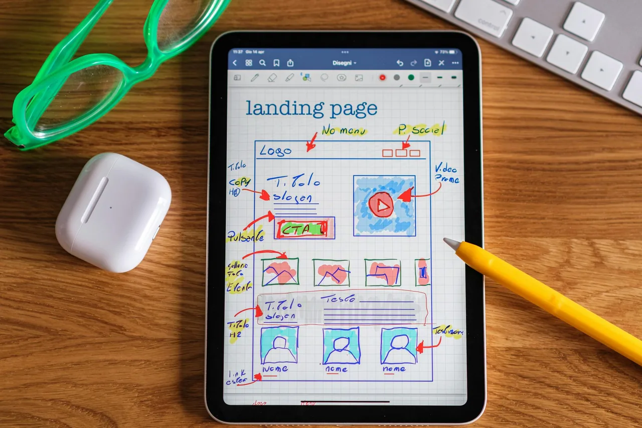 Tablet displaying a landing-page sketch beside a stylus.