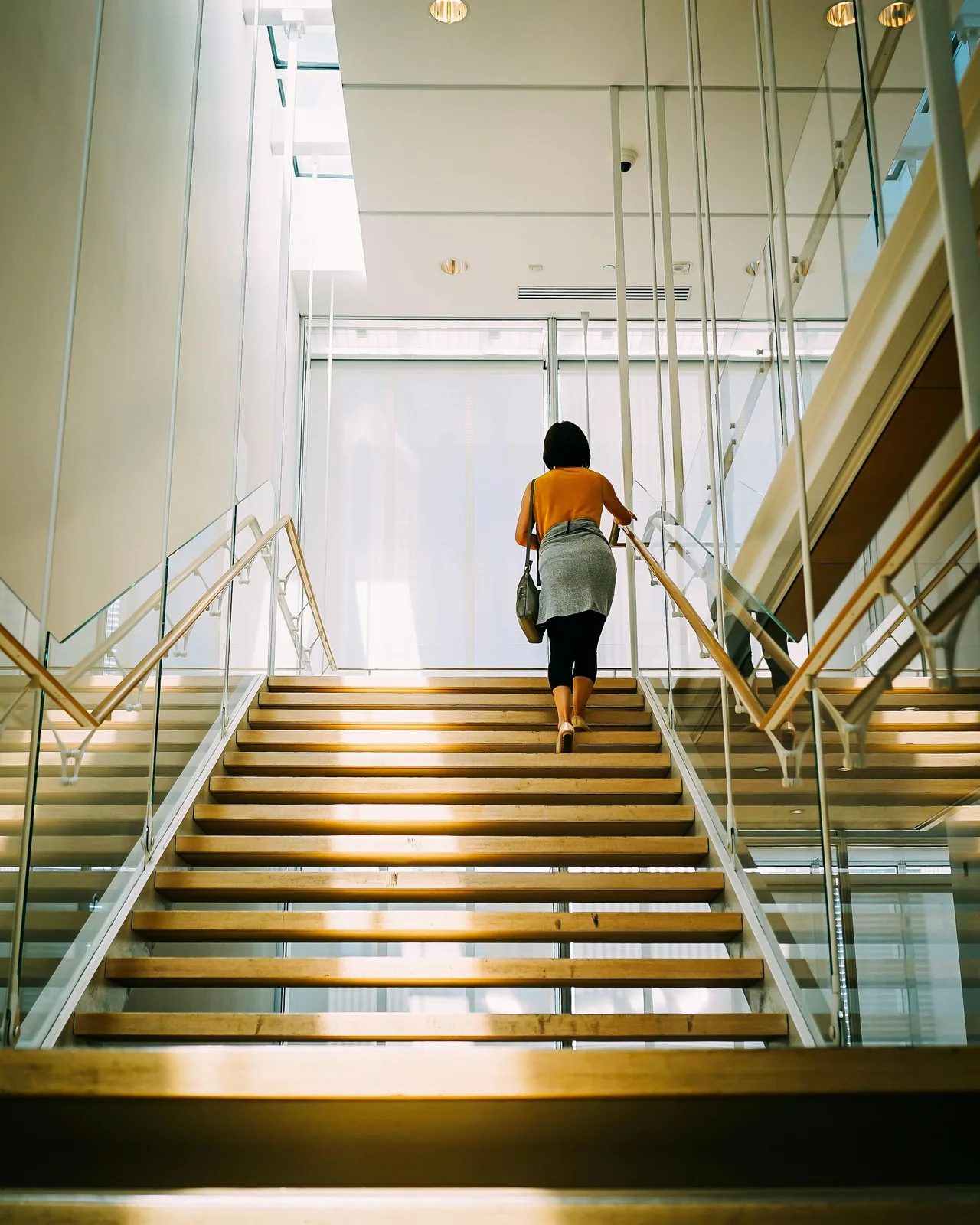 Person walking up stairs in a bright building.