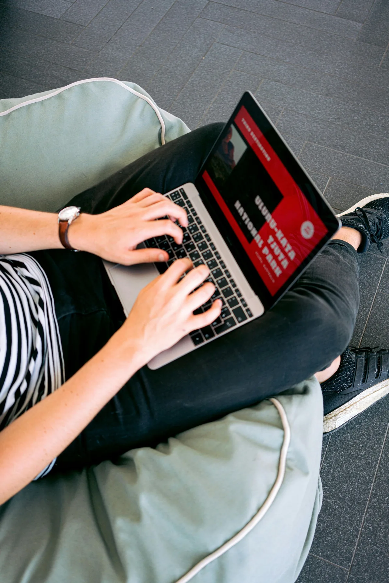 Person using a laptop while seated with a cushion.