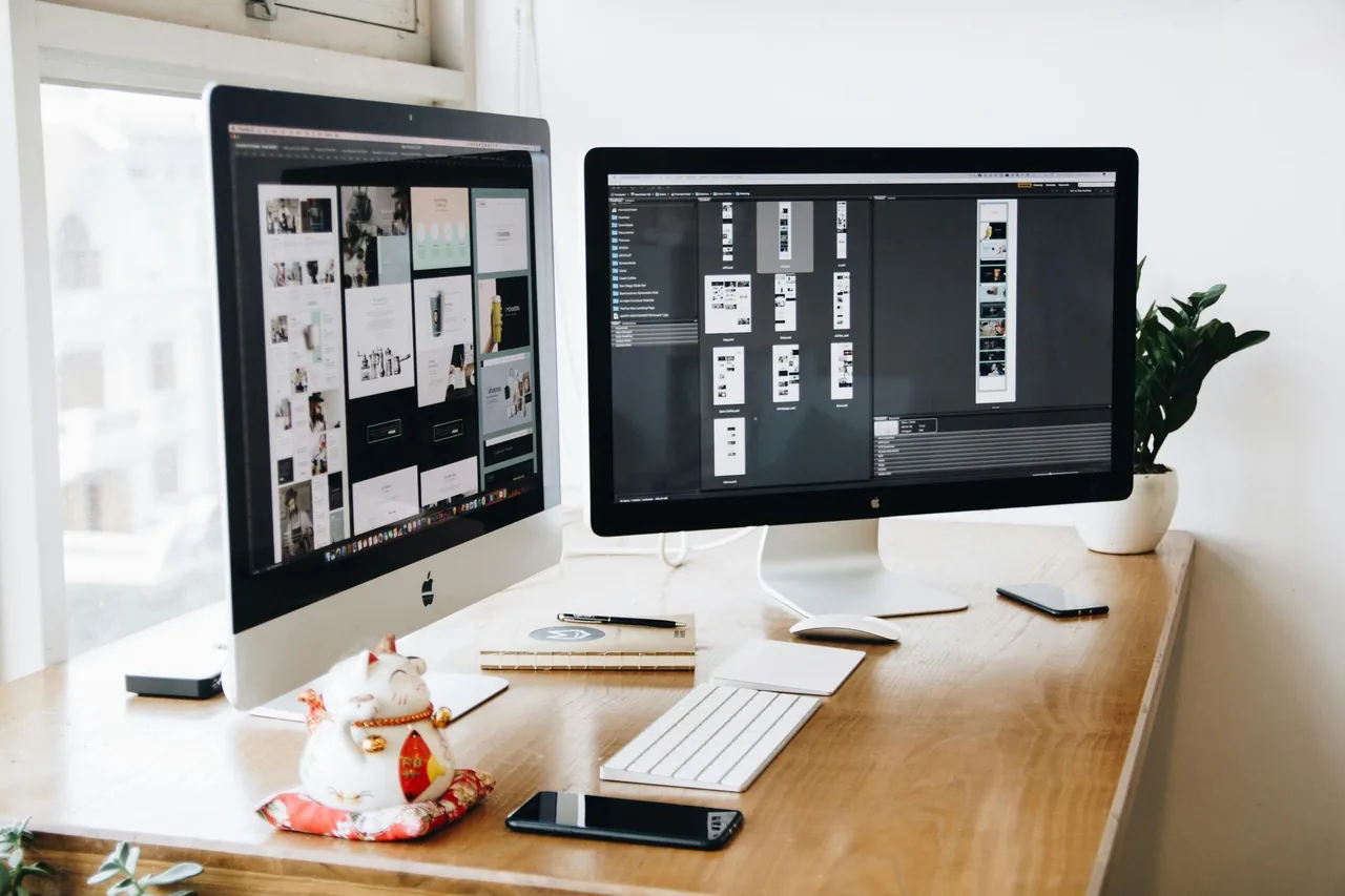 Two desktop monitors displaying website layouts.