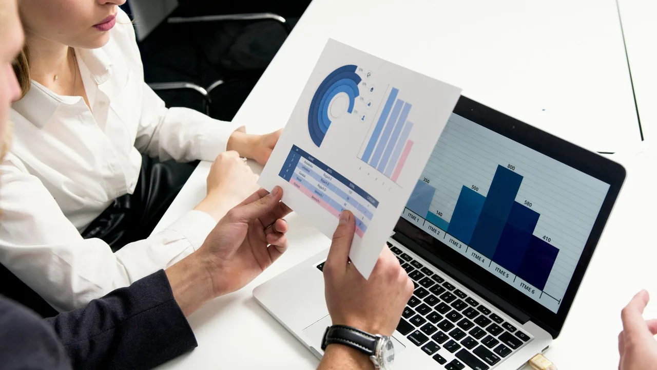 Person comparing a printed chart with figures on a laptop.