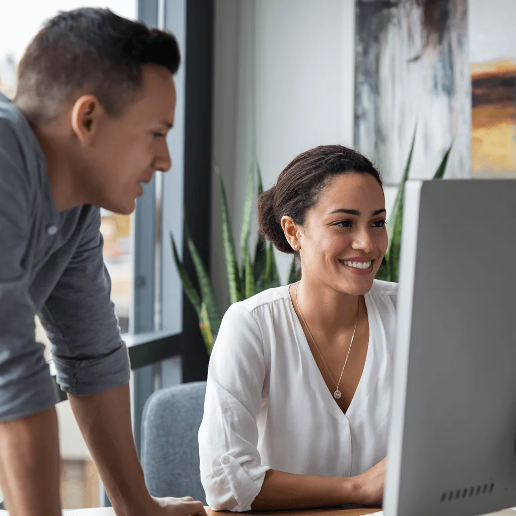 Two colleagues reviewing a desktop computer screen.